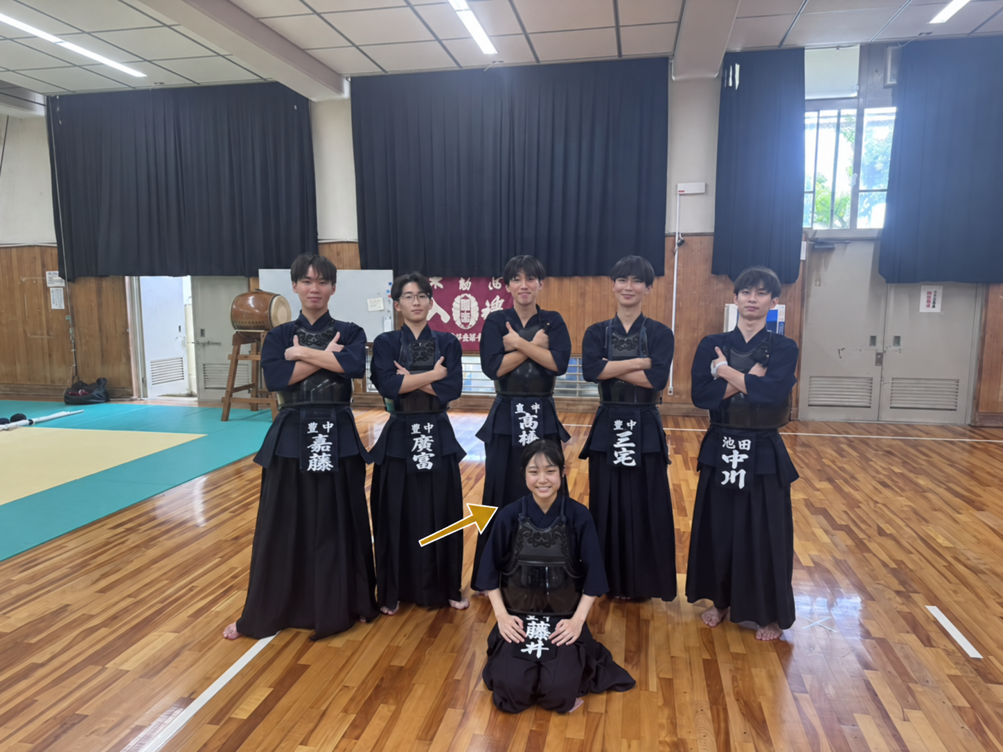 豊中高校剣道部の集合写真。手前中央の藤井さんを矢印で示しています。